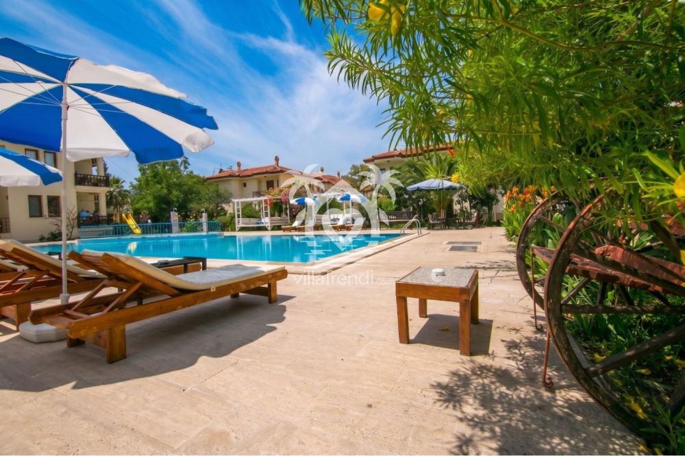 Fethiye Merkez Apart havuz başı güneşlenme alanı, şezlonglar ve şemsiyeler.