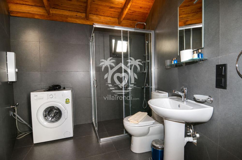 Çamaşır makinesi bulunan modern ve hijyenik kiralık ahşap villa banyosu.