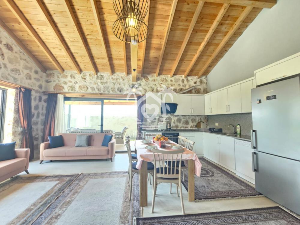 Taş mimari ve ahşap tavanlı Villa Uca 1 lüks salon ve yemek masası.