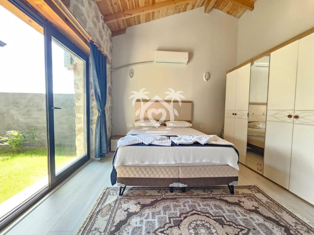 Villa Uca 1 havuz manzaralı, taş duvarlı ebeveyn yatak odası.