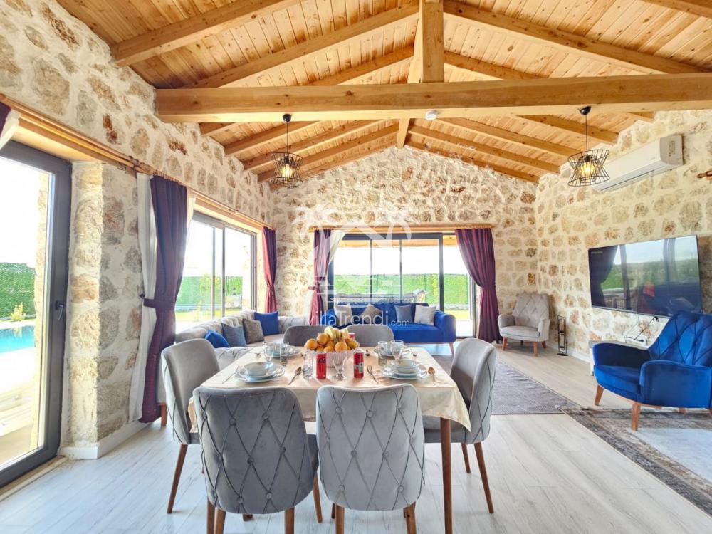 Ahşap tavanlı ve taş duvarlı Villa Uca Royal 2 ferah salon tasarımı.