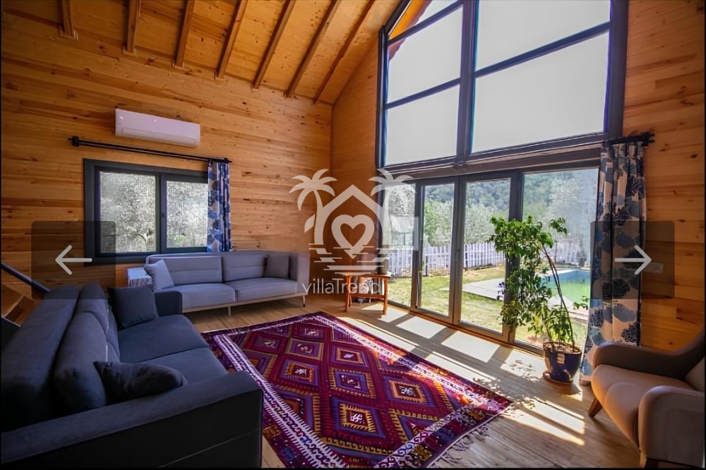 Göcek kiralık ahşap villa ferah salon ve doğa manzaralı pencereler.