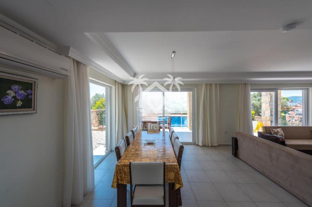 Havuz manzarasına karşı konumlanan aydınlık ve şık tasarımlı iç mekan yemek masası alanı.