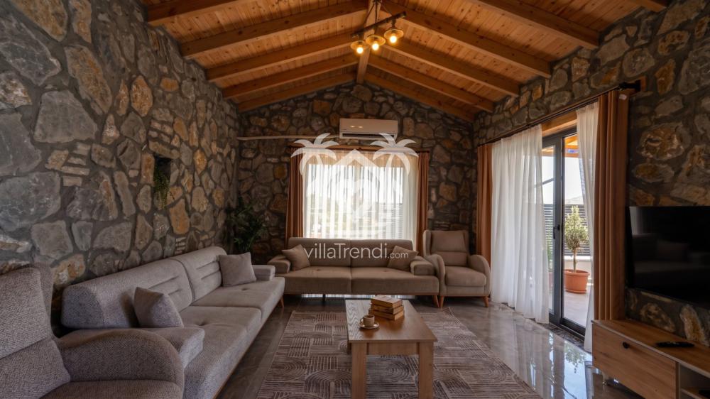 Villa Meyra taş duvarlı ferah salon ve konforlu oturma grubu.